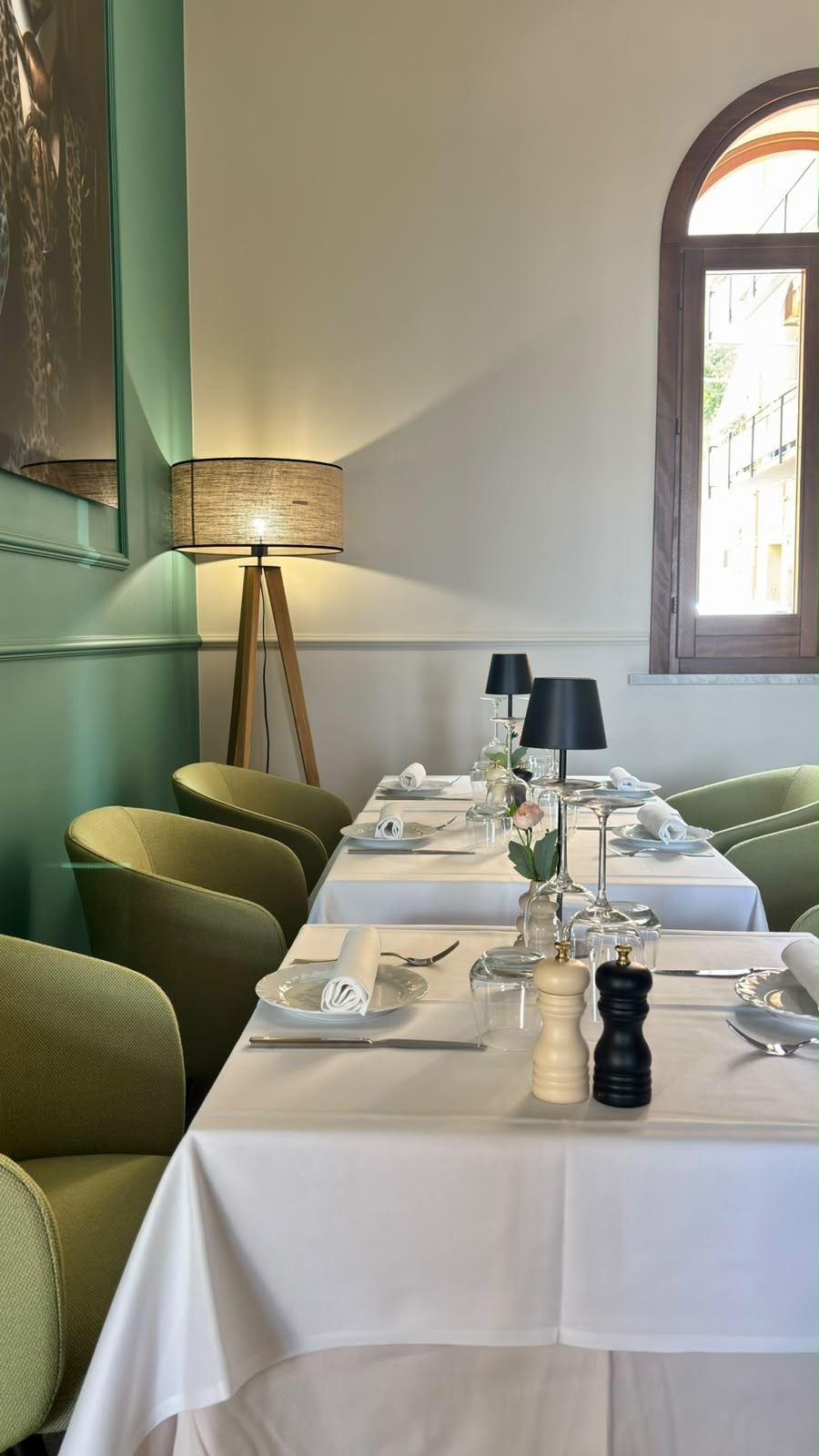 Sala verde con lampada da terra e tavoli apparecchiati