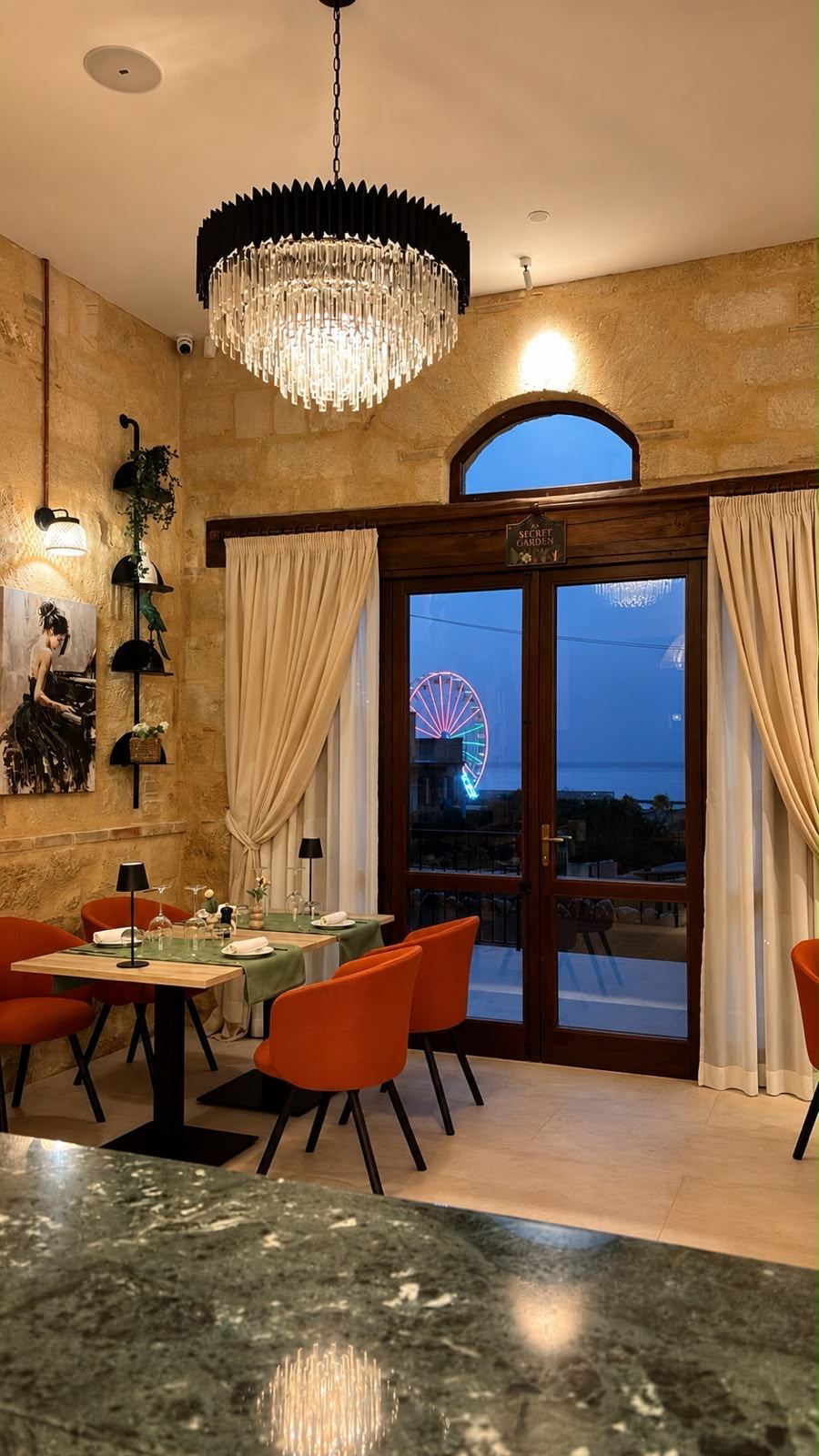 Sala del ristorante con vista sul mare e la ruota panoramica, all'imbrunire